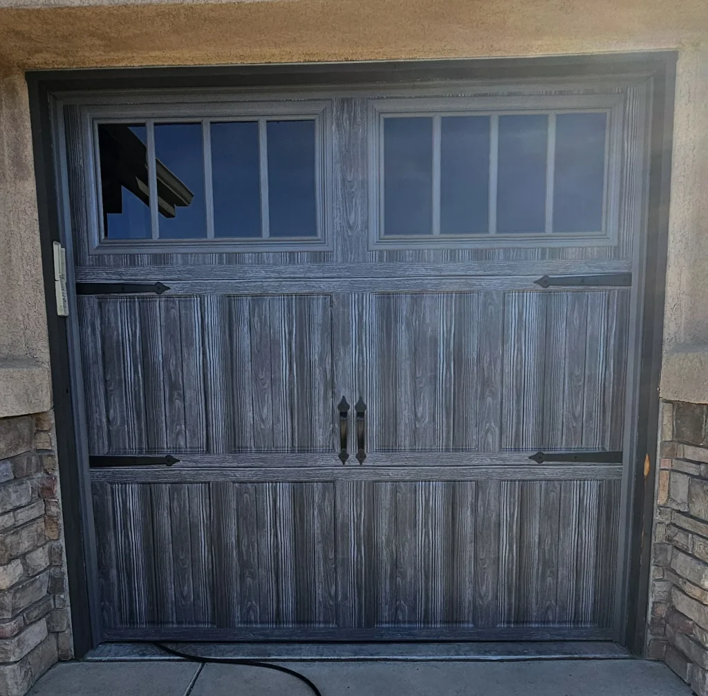 decorative black iron strap hinges and handles beneath a top row of vertically-divided window lites, as seen in the file Why Modern Wood Garage Doors Stand Out
