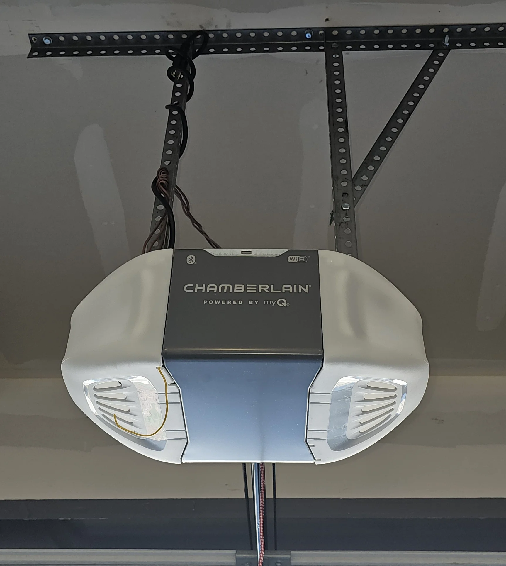 Chamberlain smart garage door opener suspended from a drywall ceiling highlights the central motor housing, a critical assembly path referenced in Garage Door Opener Components
