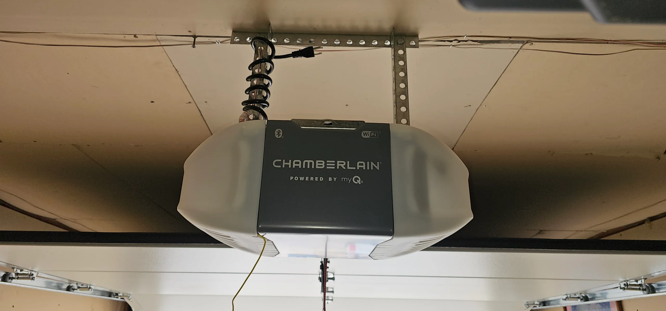 a Chamberlain smart garage door opener mounted to the ceiling panel frames the core physical setup for How Do You Adjust a Garage Door Opener