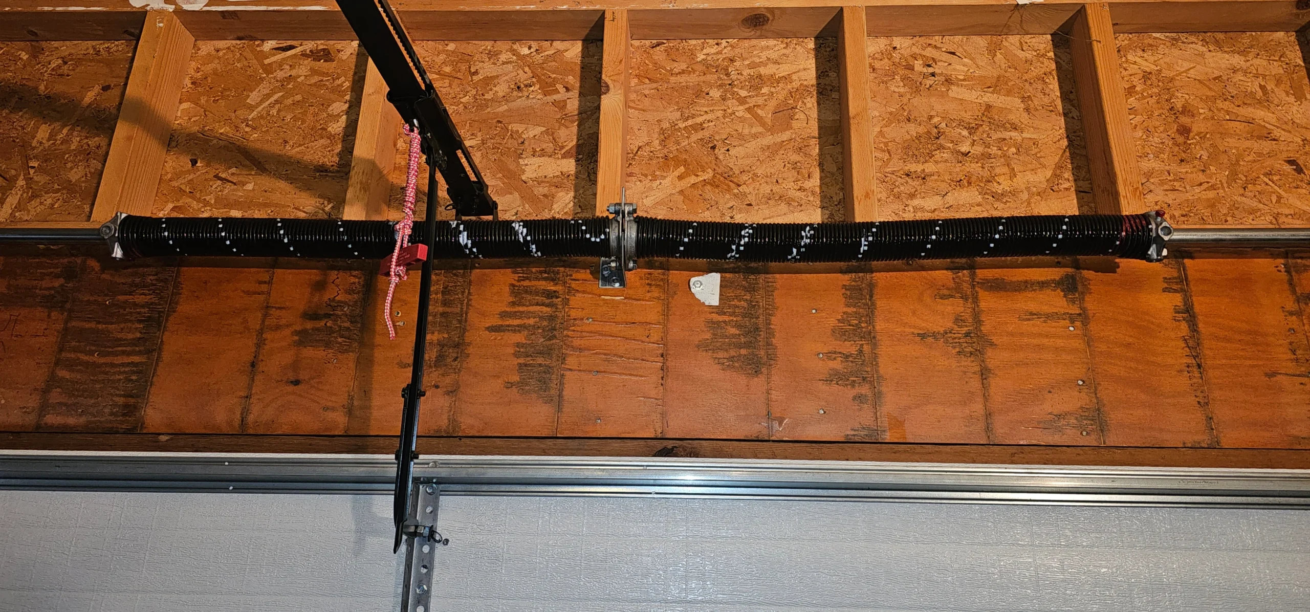 An overhead view of a freshly installed dual torsion spring assembly mounted tightly to a solid wood header plate illustrates the exact setup required for a Professional Torsion spring replacement