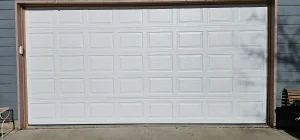 A clean, straight exterior view of a standard white double-car sectional garage door provides the visual backdrop for Garage Door Repair Cost