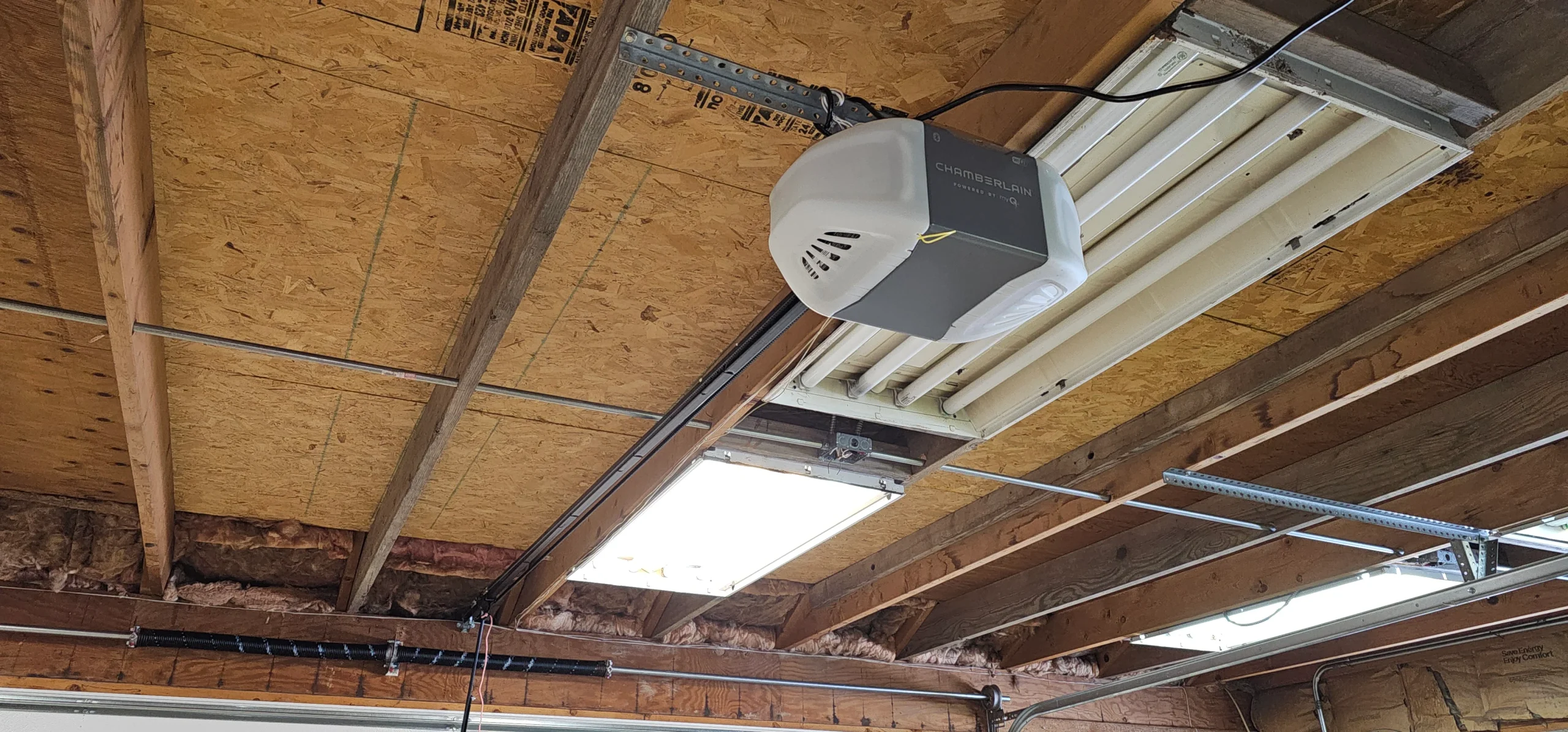 An interior view looking up at a modern, ceiling-mounted Chamberlain automatic opener highlights the structural layout discussed in Standard Garage Door Repairs