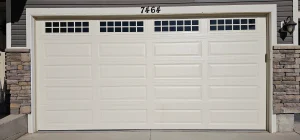 multi-panel residential garage door with top windows and surrounding stone trim provides an excellent look at the primary entry point highlighted in Garage Door Security Features