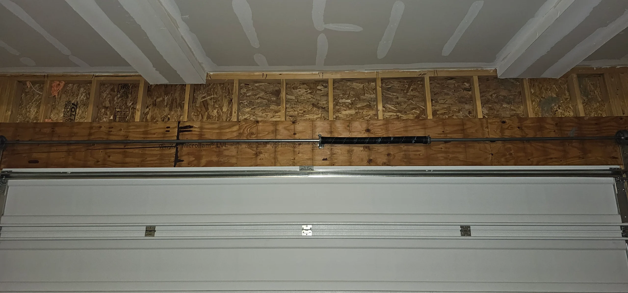 A wide, straight interior view of a closed sectional garage door frames the structural configuration in Initial System Assessment Before Spring Replacement