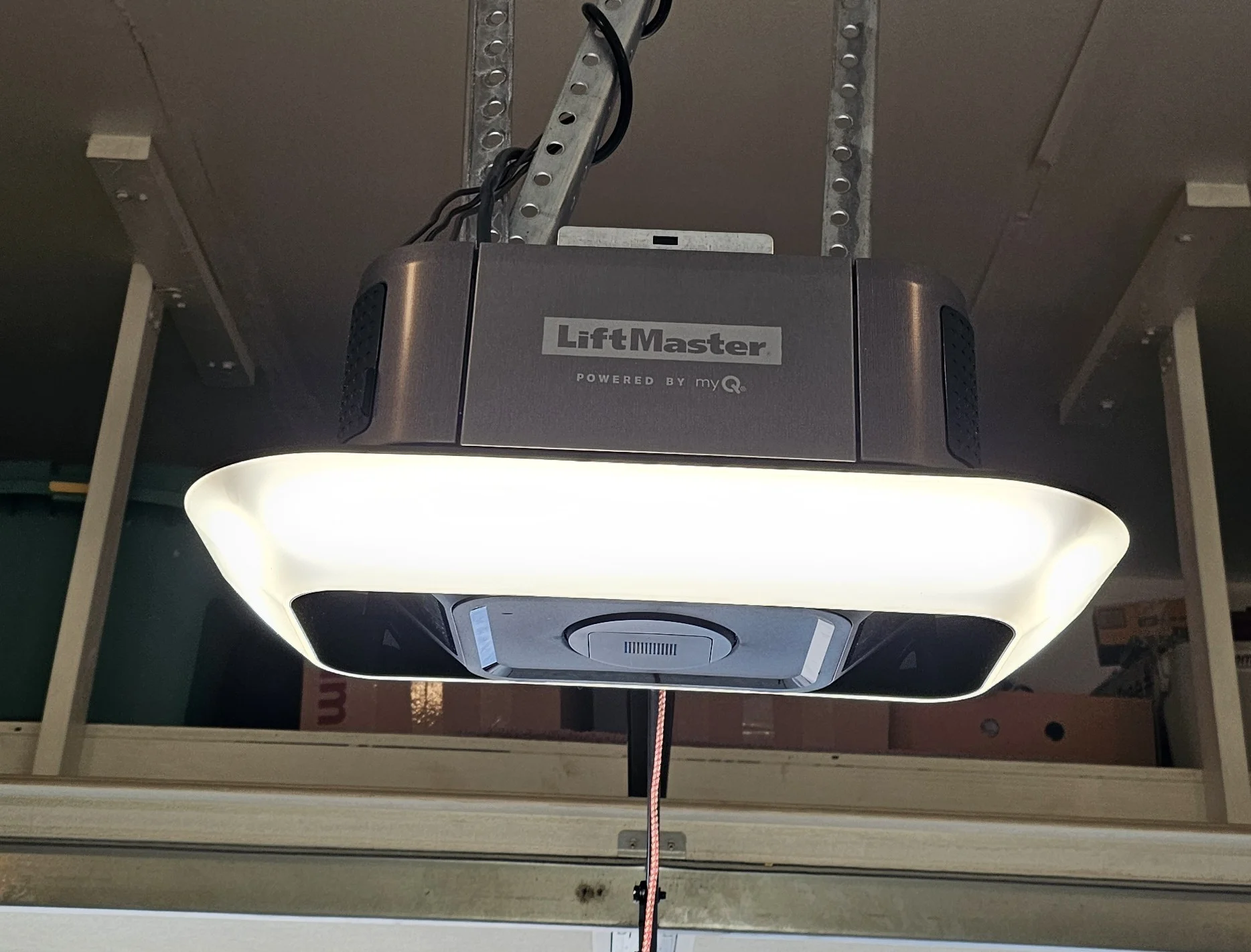 A close-up view of a LiftMaster smart garage door opener with its wrap-around courtesy light fully illuminated highlights the central unit featured in When to Worry About LiftMaster Garage Door Opener Beeping.